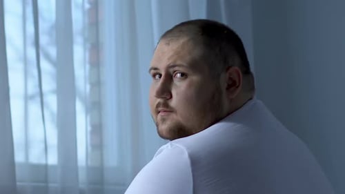 Trauriger übergewichtiger Mann blickt hoffnungslos in die Kamera, Depression verursachte Gesundheitsproblem
