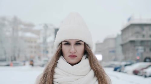 Woman Stands Still in Snowy Urban Winter Scene