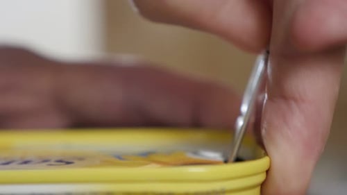 Can opened with sardine fish in oil close-up of fingers and metal opener 4K 2160p 30fps UltraHD foo