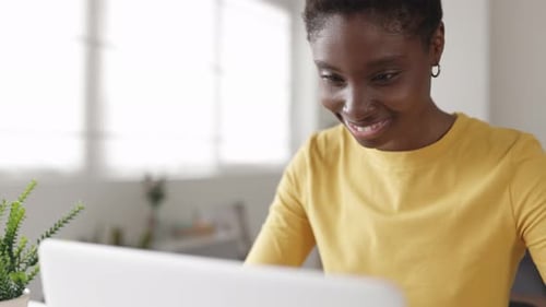 Smiling African Woman Student Using Laptop Computer for Online Learning at Home