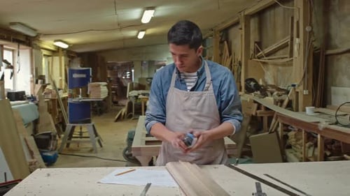 Carpenter Measuring Wood in Workshop
