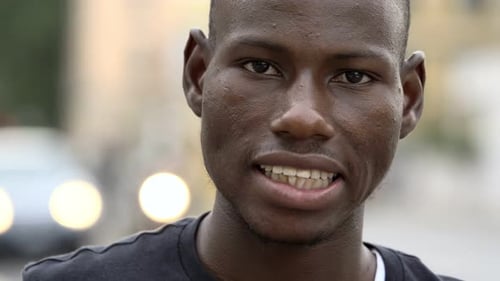 African american young man smiling at camera in the street