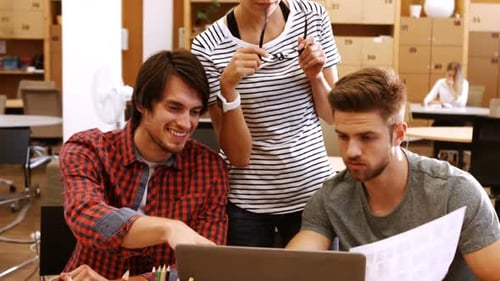 Male and female business executives discussing over laptop at their desk