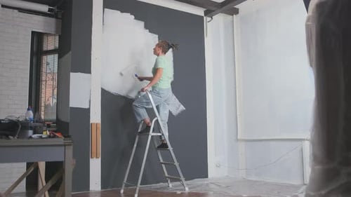 Young Adult Repainting Wall with Paint Roller