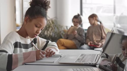 Young Student Writing in Notebook at School