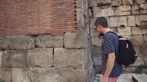 Man Walks Along Old Stone Wall in City