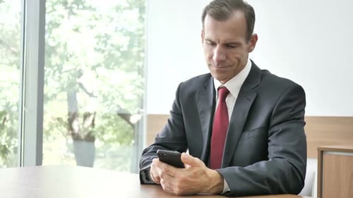 Professional Man Uses Smartphone at Office Table