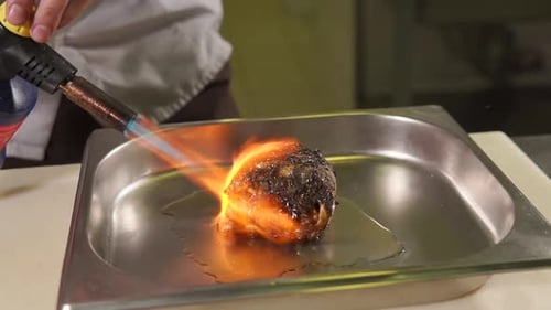 Chef searing meat with a blow torch