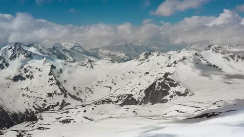 Air Flight Through Mountain Clouds Over Beautiful Snowcapped Peaks of Mountains and Glaciers