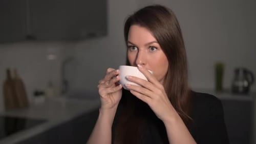 Woman Drinks from Mug in Kitchen