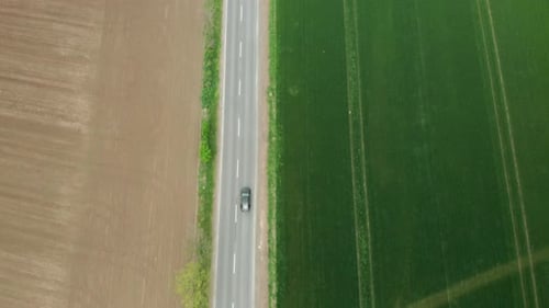 Aerial View of Moving Cars on a Fast Road Between Green and Ground Field