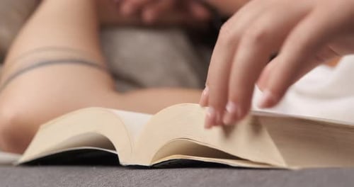 Nahaufnahme einer Frau, die ein Buch liest und auf der Couch liegt