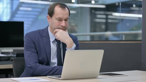 Businessman Thinking While Working on Laptop in Office
