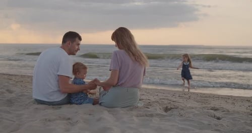 Young Parents Playing with Their Toddler Son on the Beach