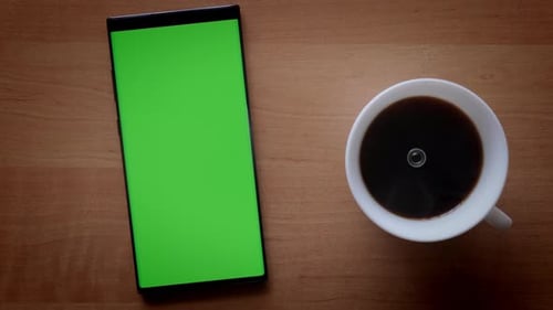 Man Hand Prepares Instant Coffee in White Cup and Phone with Green Screen on Table