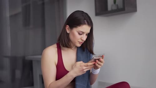 Woman Using Phone After Workout Indoors