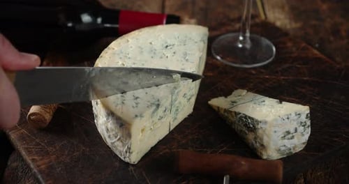 Male Hand with a Knife Cuts a Piece of Brie Cheese.