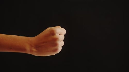 Hand Displays a Fist on a Black Background