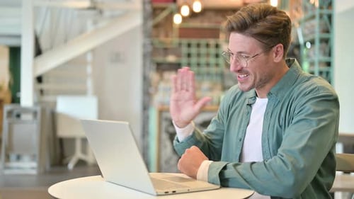 Middle Aged Man Talking on Video Chat on Laptop in Cafe
