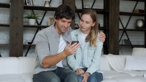 Couple Looking at a Smartphone Together on Sofa