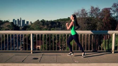Woman Running on Bridge with City Skyline