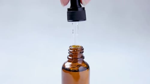 Liquid Dropping into Amber Bottle, Close Up