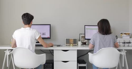 Deux indépendants au bureau à domicile. Assis au bureau blanc et travaillant sur un ordinateur.