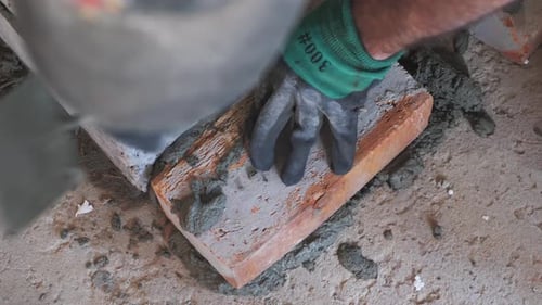 Bricklayer Applying Mortar to a Brick
