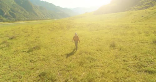 Flight Over Backpack Hiking Tourist Walking Across Green Mountain Field, Huge Rural Valley at Summer