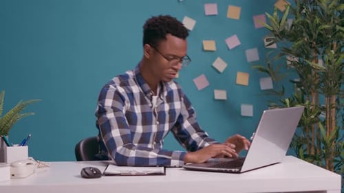 Excited Young Man Celebrating Success at Office Desk