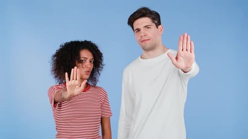 Interracial Serious Couple zeigt ablehnende Geste von Stop Palm Hand Schild