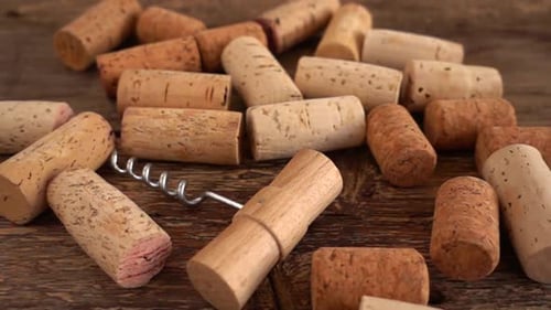 Corchos de vino y sacacorchos que caen sobre tablas viejas de madera. A cámara lenta.