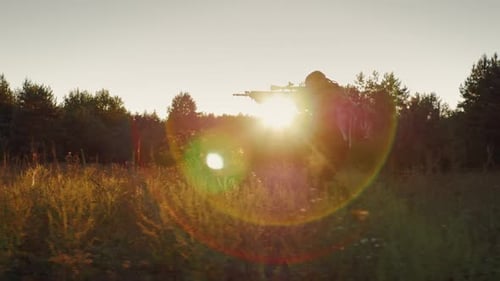 Soldier Running with Rifle in Grassy Field at Sunset