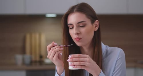 Young Woman Eating Yogurt in Modern Kitchen