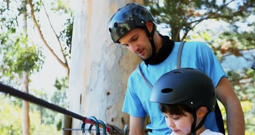 Man assisting child to fix carabiner on zip line 4K 4k
