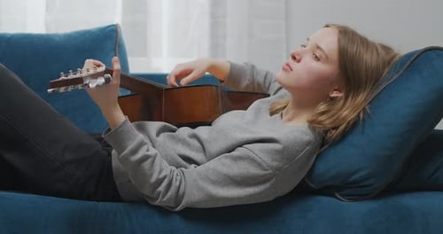 Side View of a Romantic Girl with Blond Hair Lies on the Sofa at Home