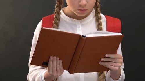 Focused Girl Reads a Book in School