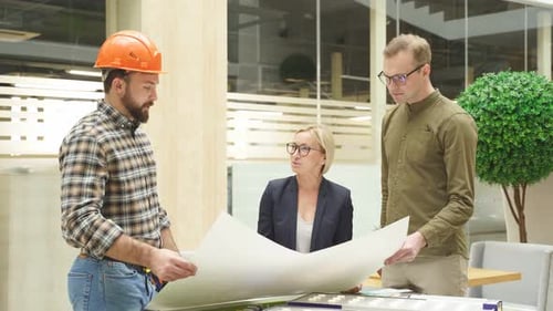 Un architecte confiant montre un plan de construction à des ingénieurs de premier plan