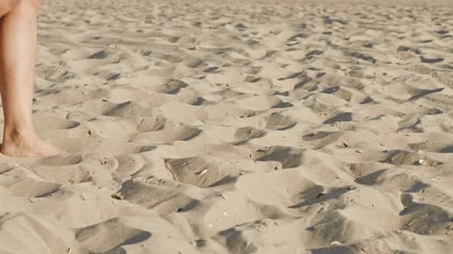Legs of Girl Walking Barefoot Sand on Sea Beach or Desert. Slow Motion. Woman Walks Past the Camera