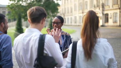 Retrato de uma linda jovem afro-americana feliz encontrando colegas de grupo após as férias se abraçando