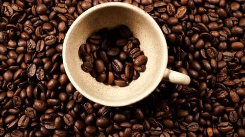 Coffee Beans Filling a Beige Ceramic Cup