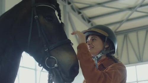 Female Jockey Stroking Horse and Smiling