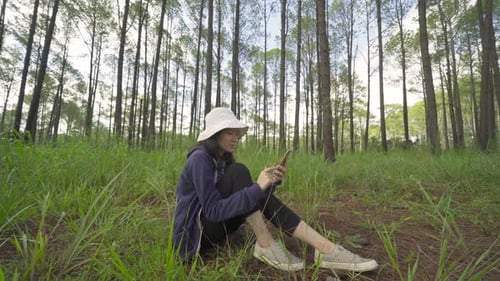 Young Woman Using Phone in a Forest