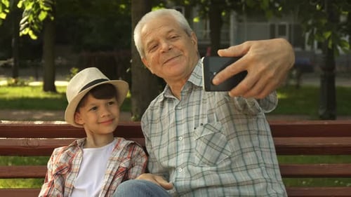 Grandfather and Grandson Taking Selfie in Park