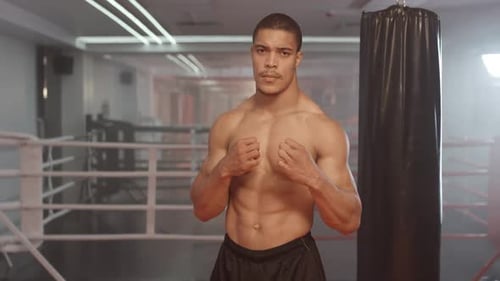 Kickboxing, Athletic Man Fighter Trains in Boxing Gym, a Muscular Man Takes a Fighting Stance and