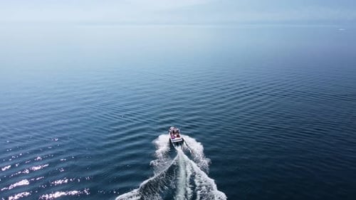 Small speed boat heading off into the distance on Okanagan Lake during the hottest summer in Canadia