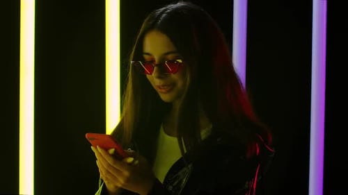 Stylish Woman Using Smartphone with Neon Lights