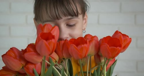 Girl Smells Red Tulips in Bouquet Close Up