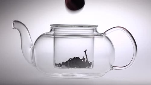Tea Leaves Dropping Into Clear Glass Teapot