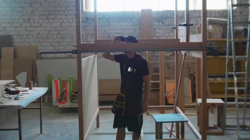 Carpentry Works in Workshop Man Worker Standing in the Unfinished Wooden Construction